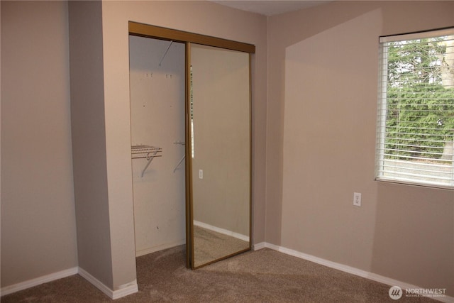 unfurnished bedroom with carpet, a closet, and baseboards