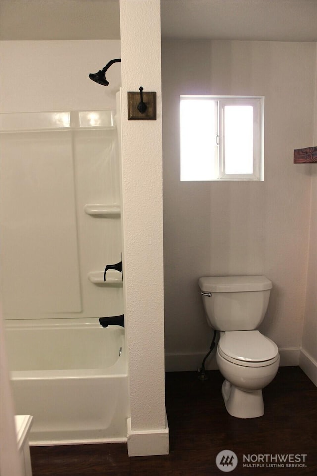 bathroom with baseboards, toilet, bathtub / shower combination, and wood finished floors