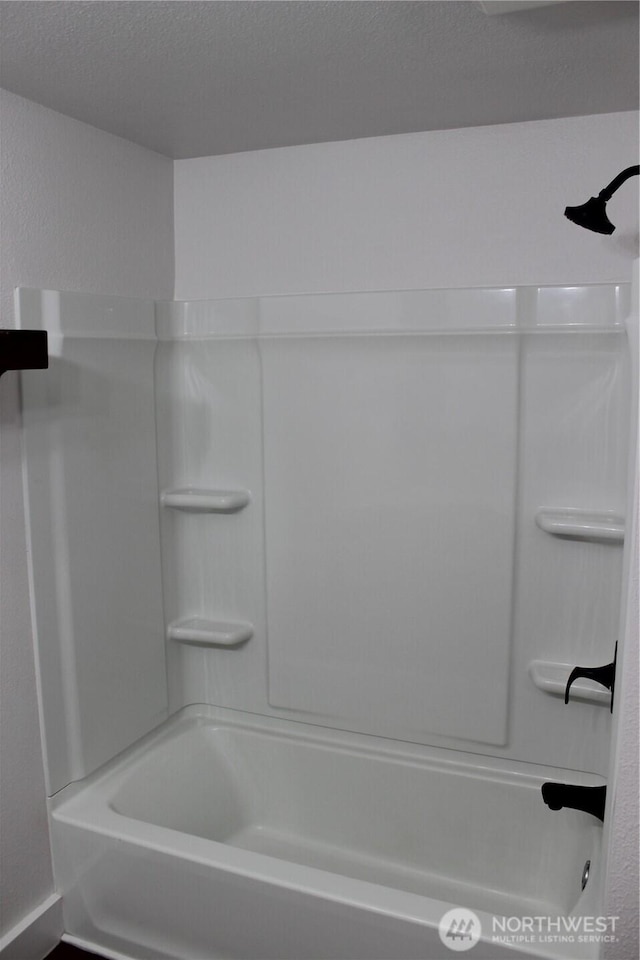 bathroom featuring shower / bathing tub combination and a textured ceiling