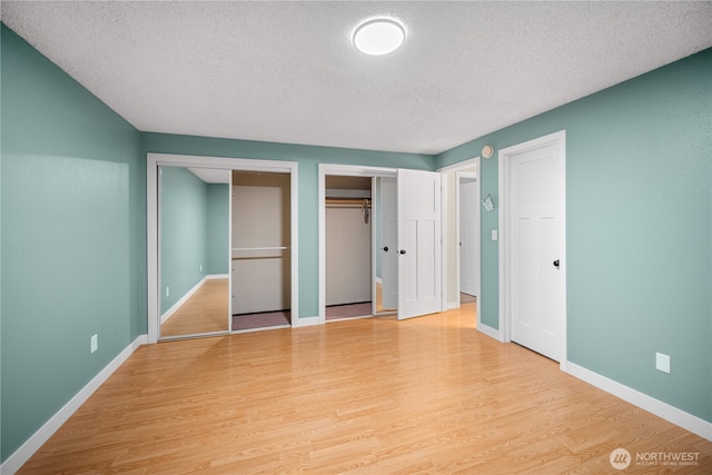 315 Point Fosdick Pl NW, Gig Harbor, WA 98335 - unfurnished bedroom featuring wood finished floors, baseboards, two closets, and a textured ceiling