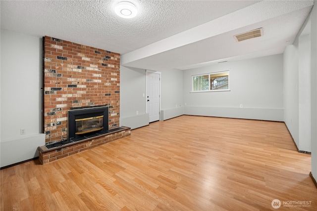 315 Point Fosdick Pl NW, Gig Harbor, WA 98335 - unfurnished living room with visible vents, a brick fireplace, a textured ceiling, and wood finished floors