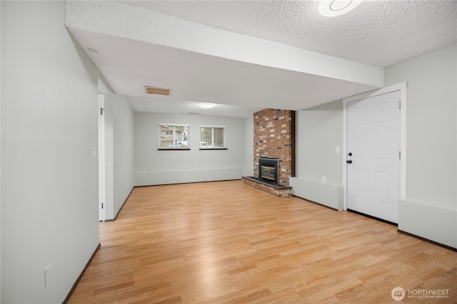 315 Point Fosdick Pl NW, Gig Harbor, WA 98335 - unfurnished living room with visible vents, a textured ceiling, light wood-style flooring, and a fireplace