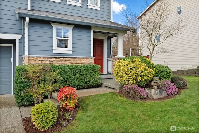 property entrance with a garage, a lawn, stone siding, and roof with shingles