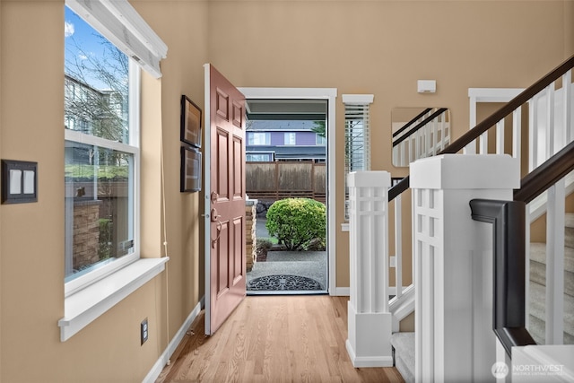 entryway with stairs, baseboards, and wood finished floors