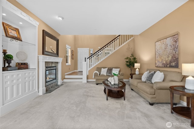 carpeted living room featuring stairway, baseboards, and a tile fireplace