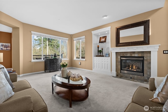 living room with baseboards, carpet flooring, and a tiled fireplace