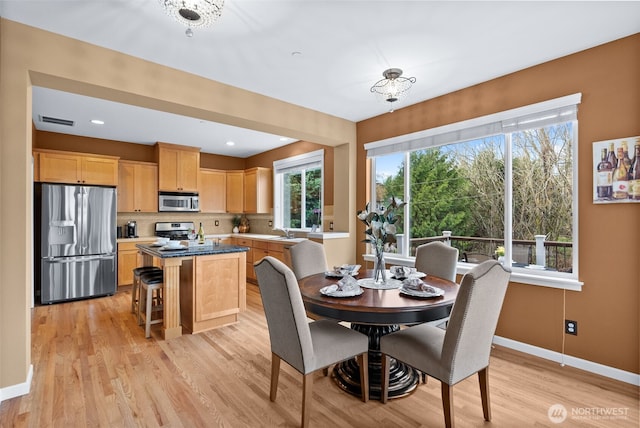 dining area with light wood-style flooring, baseboards, and visible vents