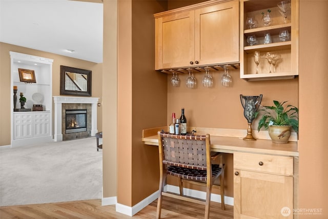 bar with built in features, light wood finished floors, baseboards, a dry bar, and a tile fireplace