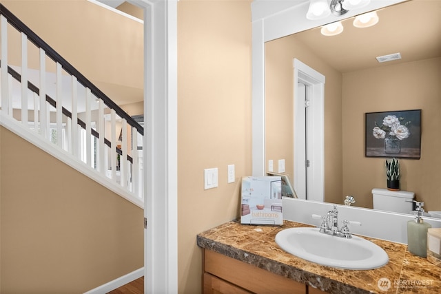 bathroom featuring vanity, toilet, baseboards, and visible vents