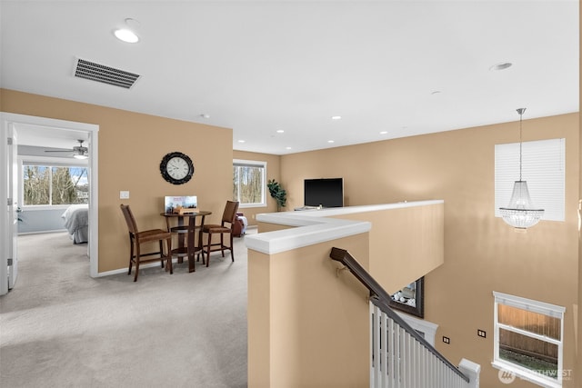 corridor featuring plenty of natural light, an upstairs landing, visible vents, and light carpet