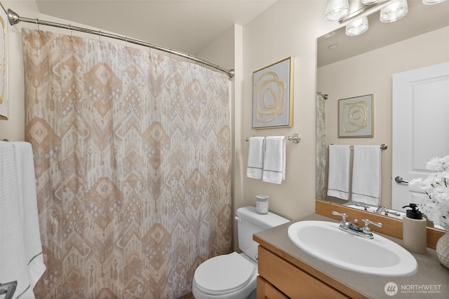 bathroom featuring toilet, vanity, and a shower with curtain