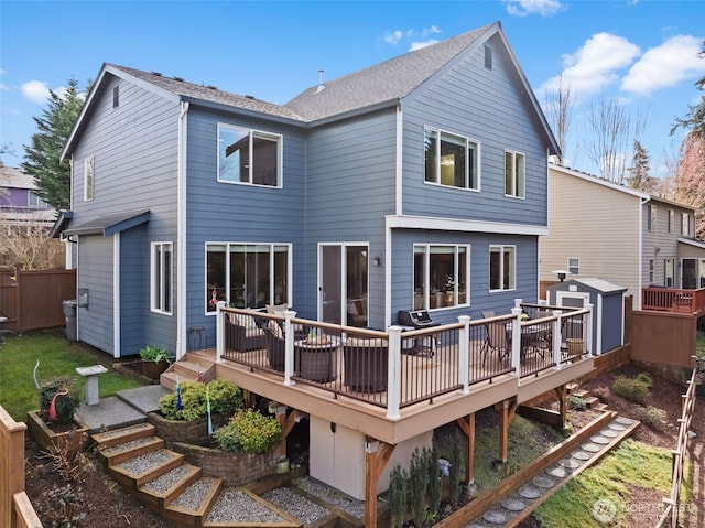 back of property with a deck, an outdoor structure, a storage unit, and fence