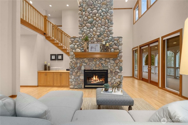 living room featuring french doors, baseboards, a stone fireplace, and wood finished floors