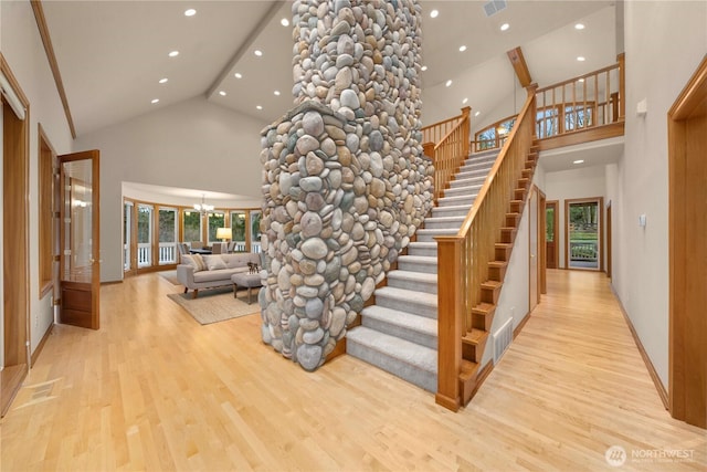 staircase featuring a wealth of natural light, high vaulted ceiling, and wood finished floors