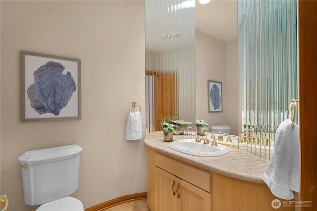 bathroom with baseboards, toilet, and vanity