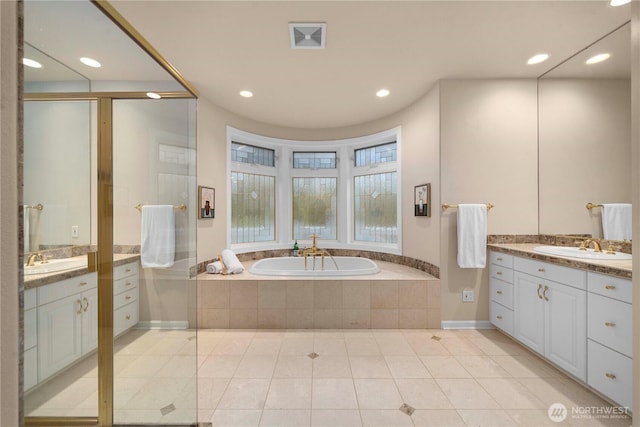 bathroom with a sink, a garden tub, two vanities, and tile patterned flooring