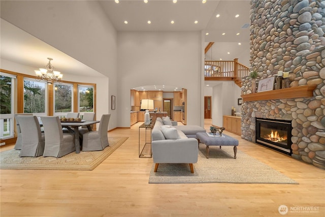 living area with light wood finished floors, recessed lighting, a fireplace, and an inviting chandelier