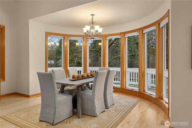 dining room featuring baseboards, plenty of natural light, a notable chandelier, and light wood-style flooring