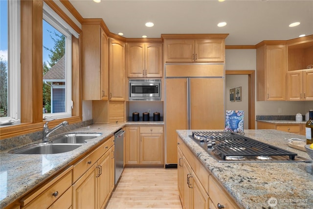 kitchen with a sink, recessed lighting, light wood-style floors, built in appliances, and light stone countertops