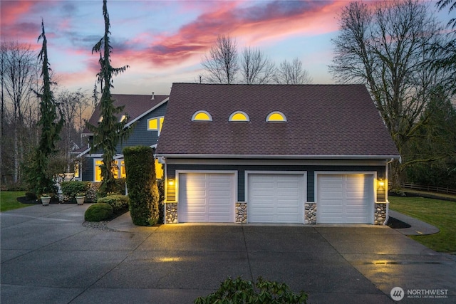 view of front of home featuring stone siding, a garage, and roof with shingles