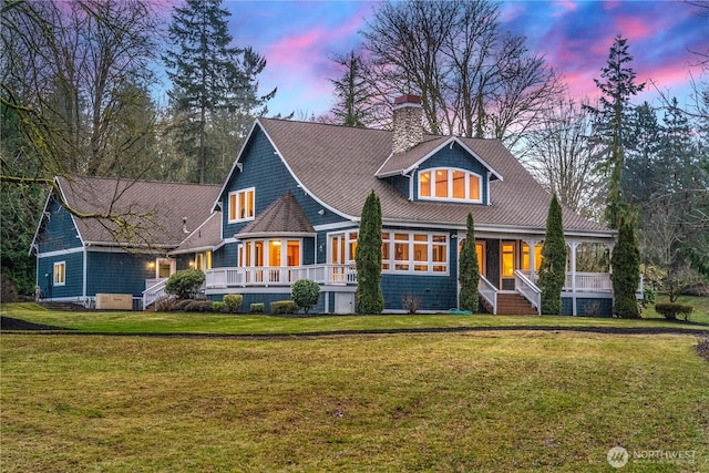 view of front of house featuring a porch, a yard, and a chimney