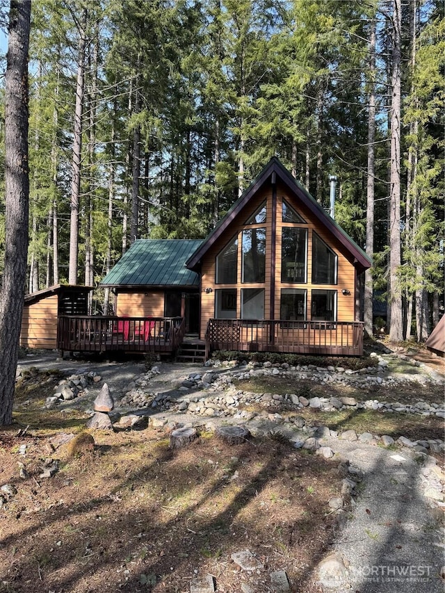 rear view of house with a deck and a forest view