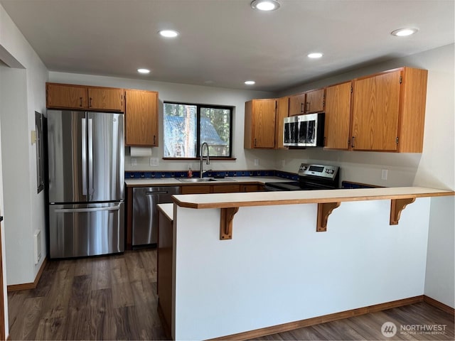 kitchen featuring a sink, dark wood-style floors, recessed lighting, a peninsula, and appliances with stainless steel finishes