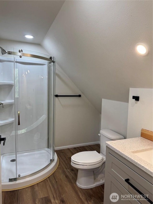 full bath featuring toilet, a stall shower, wood finished floors, vanity, and vaulted ceiling