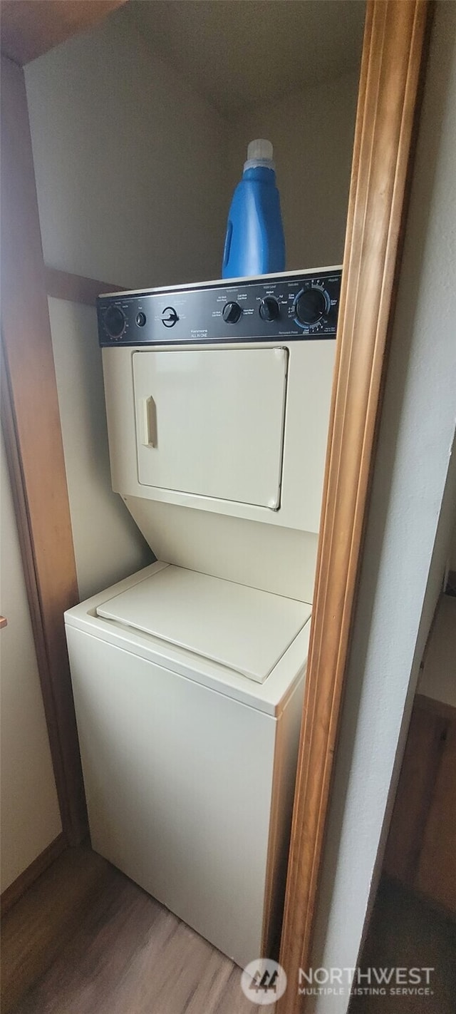 washroom with laundry area, stacked washing maching and dryer, and wood finished floors