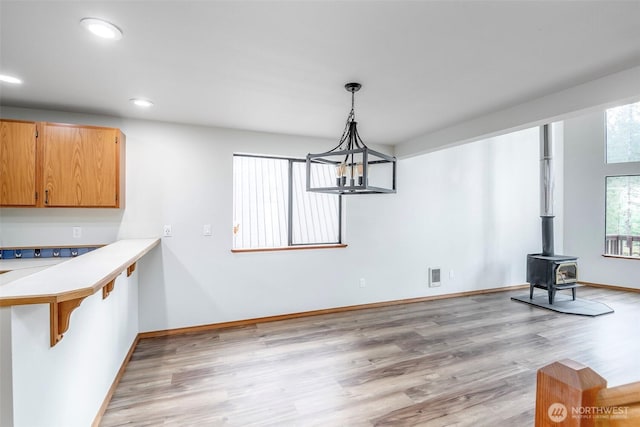 213 Crescent Beach Dr, Packwood, WA 98361 - unfurnished dining area featuring recessed lighting, an inviting chandelier, a wood stove, and light wood-type flooring