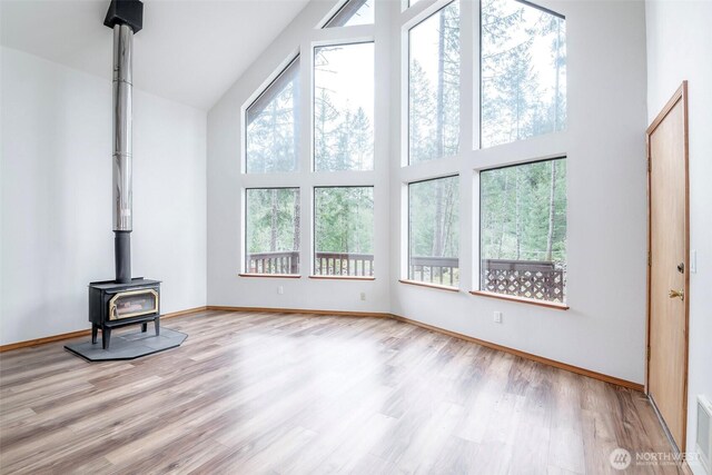 213 Crescent Beach Dr, Packwood, WA 98361 - unfurnished living room featuring wood finished floors, a wood stove, baseboards, a high ceiling, and visible vents