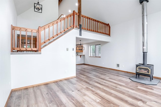 213 Crescent Beach Dr, Packwood, WA 98361 - unfurnished living room with light wood-type flooring, baseboards, visible vents, high vaulted ceiling, and a wood stove