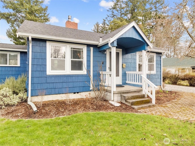 view of front facade with crawl space, a front lawn, a chimney, and roof with shingles