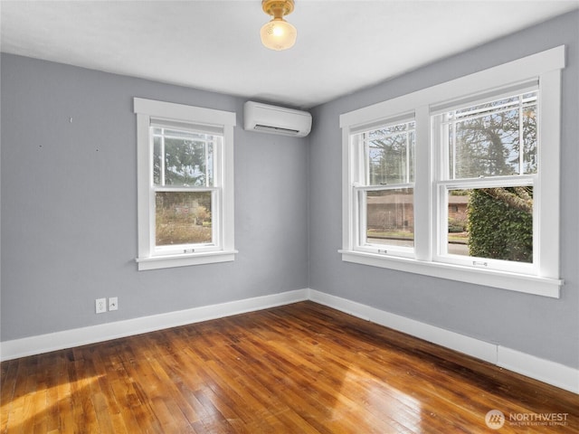 unfurnished room with a wealth of natural light, an AC wall unit, baseboards, and wood-type flooring