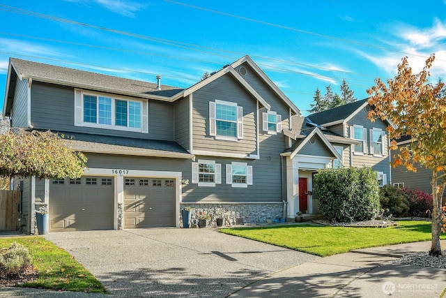 view of front of house with stone siding, an attached garage, concrete driveway, and a front yard