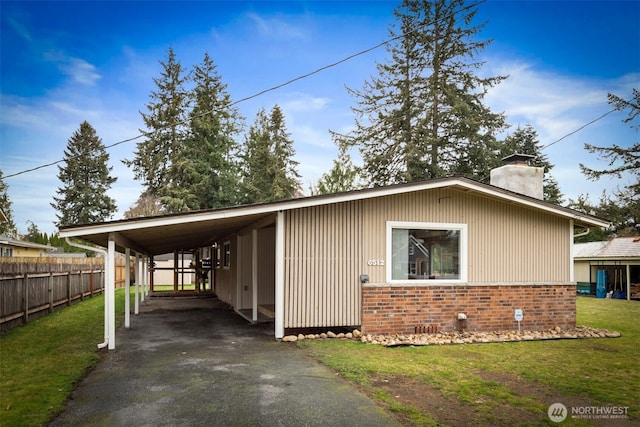 exterior space featuring an attached carport, a front lawn, fence, a chimney, and driveway