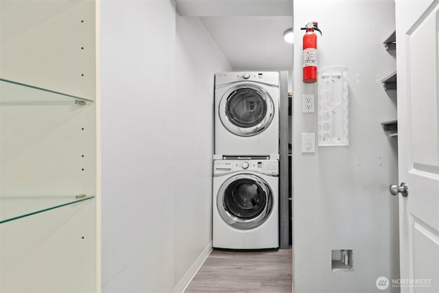 laundry area featuring laundry area, stacked washer and clothes dryer, and wood finished floors