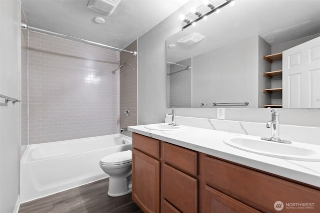 bathroom featuring toilet, wood finished floors, shower / bath combination, and a sink