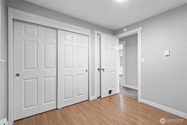 unfurnished bedroom with baseboards, light wood-type flooring, and a closet