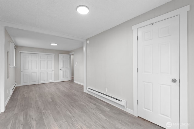 unfurnished bedroom with a baseboard heating unit, wood finished floors, and a closet