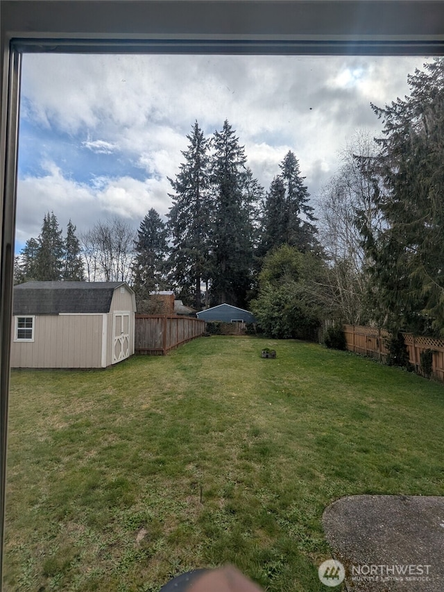 view of yard featuring an outbuilding, a shed, and fence