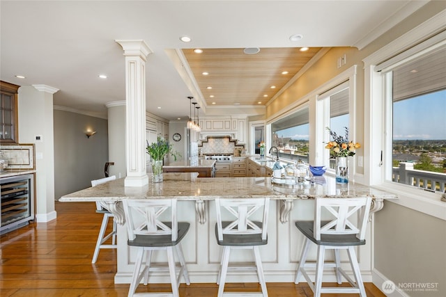 5685 Nakat Way, Blaine, WA 98230 - kitchen with wine cooler, ornate columns, hardwood / wood-style flooring, recessed lighting, and backsplash