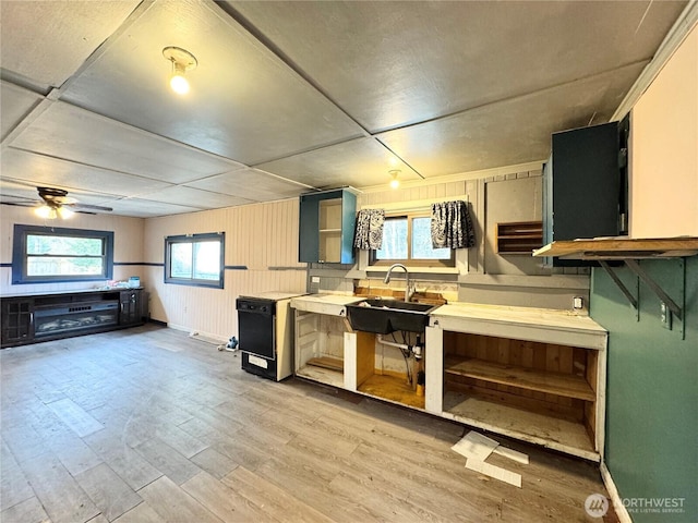 kitchen featuring light wood-type flooring, a sink, light countertops, baseboards, and ceiling fan