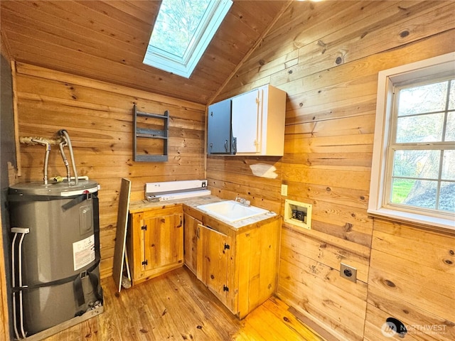 interior space with a skylight, wooden walls, electric water heater, and a sink