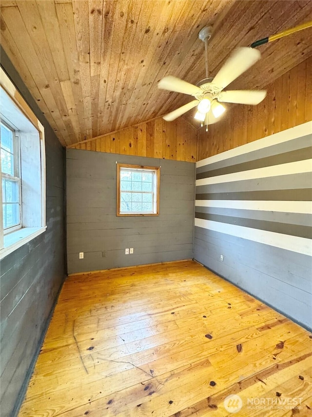 spare room with a ceiling fan, hardwood / wood-style flooring, wood walls, lofted ceiling, and wood ceiling