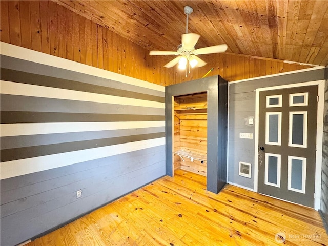 unfurnished bedroom with wooden walls, visible vents, wood ceiling, vaulted ceiling, and hardwood / wood-style floors