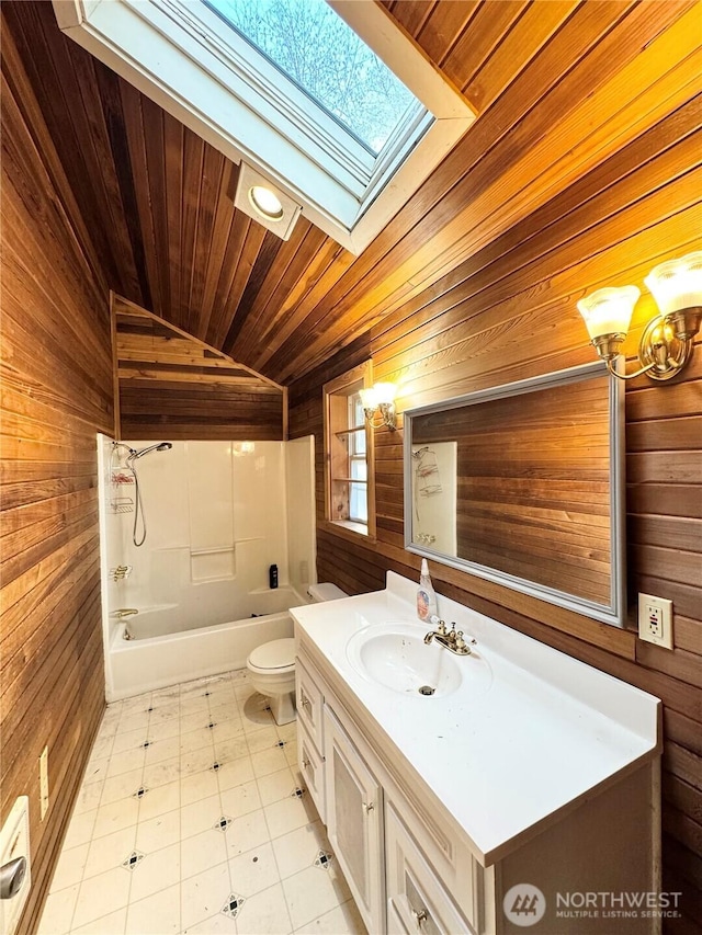 full bathroom with wood walls, toilet, vaulted ceiling with skylight, bathing tub / shower combination, and vanity