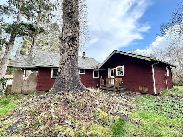 rear view of house with a chimney and a shingled roof