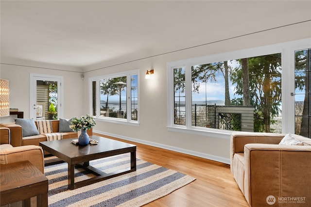 living room with baseboards, an inviting chandelier, and light wood-style flooring