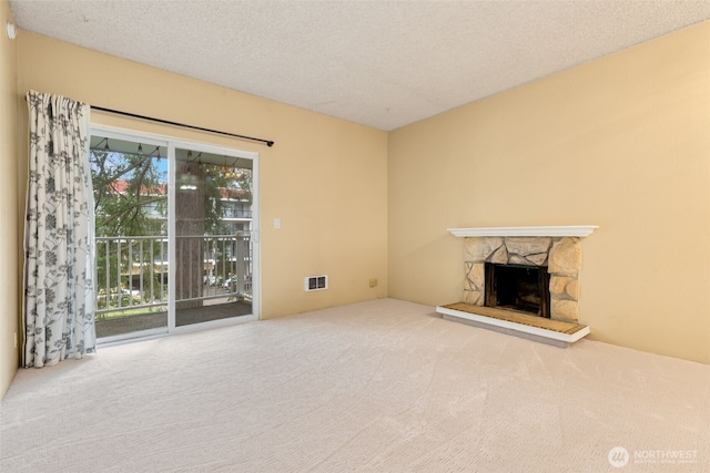 unfurnished living room with visible vents, a fireplace, a textured ceiling, and carpet